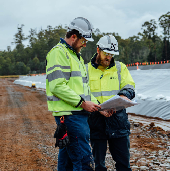 Two people in high-vis looking at plans on a worksite