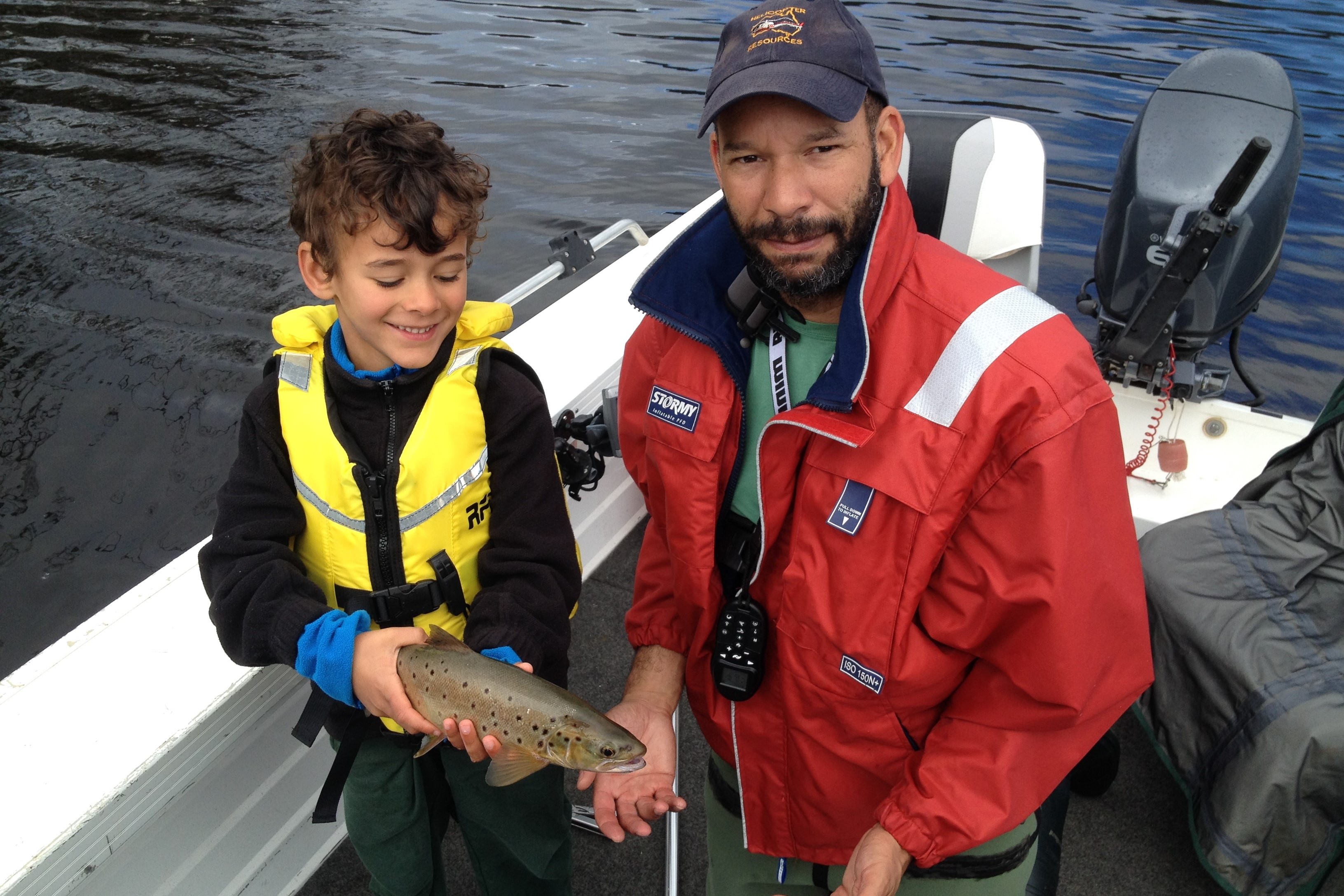 Man and boy in a boat holding a fish