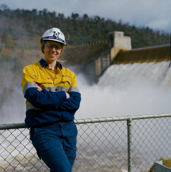 Person standing in front of a dam wearing high-vis and a Hydro Tasmania hardhat