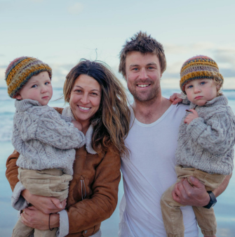 A family smiling for the camera (man, women, and two twin children), with a dusty sunset behind them.